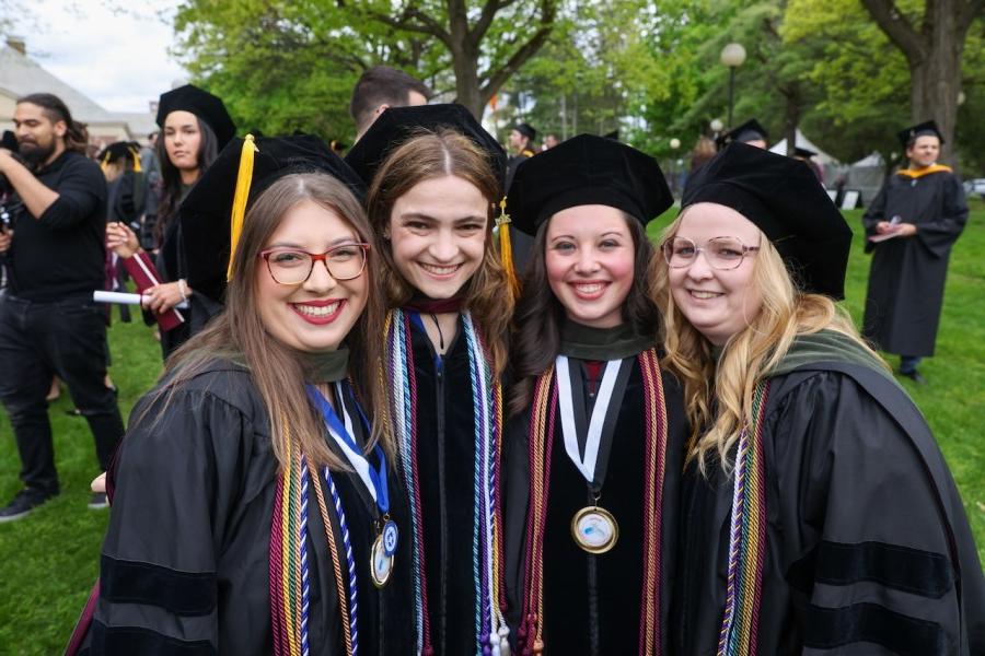 New grads smile in cap and gown at graduation