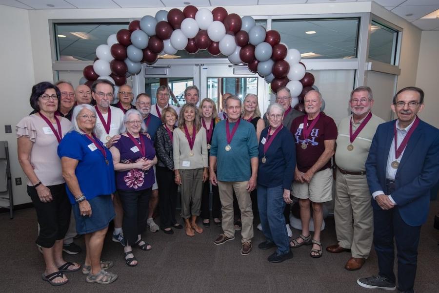 Alumni gather together in front of balloons